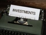 a close up of a typewriter with a paper that reads investments