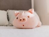 A cute pink pig plush toy on a bed.