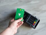 a hand holding a green card next to a calculator