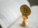 bitcoin on gold stand on top of book