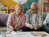 Elderly couple looking at bills and phone