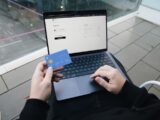 A person sitting in a chair with a laptop and a credit card