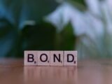 The word bond spelled with scrabble blocks on a table
