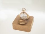 Antique gold pocket watch on display stand