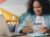 Teenager using phone and credit card for online shopping.