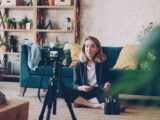 Woman filming herself with a camera in a living room.
