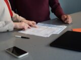 Two people reviewing documents at a table.