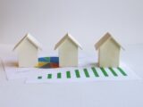 three small houses sitting on top of a piece of paper