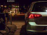 silver Volkswagen Golf station wagon parked beside gas pump during nighttime