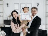Happy multicultural family celebrating adoption with certificate indoors.