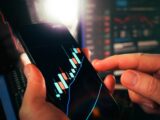 Hands holding smartphone showing stock market data
