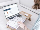 a person sitting on a bed with a laptop