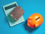 Calculator, piggy bank, and house model on blue background