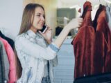 Woman shops for clothes while on a phone call.