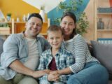 A happy family of three sitting on a couch.