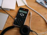 black scientific calculator beside black headphones