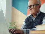Elderly man with glasses using a laptop