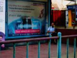 Man sitting at a bus stop with advertisement