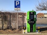 a green parking meter next to a parking sign