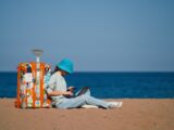 a person sitting on the beach with a suitcase