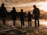 a family walking on the beach at sunset