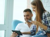 Couple happily shopping online with tablet and credit card.