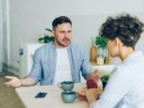 a man sitting at a table talking to a woman