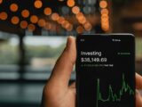 a person holding up a cell phone with a stock chart on it
