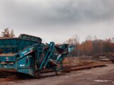 green and black heavy equipment on brown dirt road during daytime