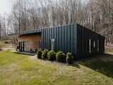 a small black cabin in the middle of a field