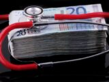a medical stethoscope resting on a stack of money