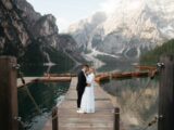 A bride and groom are standing on a dock
