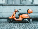 orange and black motor scooter parked on pavement