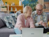 Elderly couple shopping online with credit card and laptop.