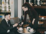 A woman serves coffee to a man in a cafe