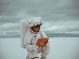 woman in white long sleeve shirt holding orange smartphone