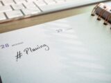 a notepad with a planner and a keyboard in the background