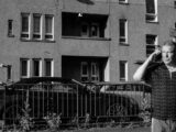 Man talking on phone walks past a city building