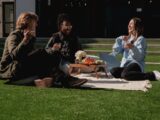 Three friends enjoying a picnic on the grass