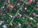 Aerial view of infrastructure of tropical countryside with residential cottages and green trees in daytime