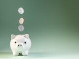 Coins falling into a white piggy bank
