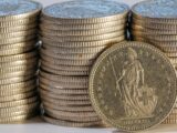 Stacks of gold coins with one coin in front