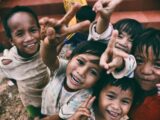 five children smiling while doing peace hand sign