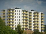 a tall white building with yellow balconies