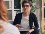 a woman sitting on a couch talking to another woman