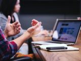 person gesturing during meeting with laptop