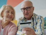 Elderly couple looking at credit card and laptop