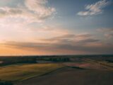 brown field under white clouds during daytime