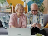 Elderly couple using laptop and credit card at home