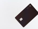 A black business credit card with a chip on a white background